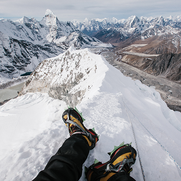 Photo of a mountain climber and his boots on top a snowy summit